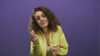 © Krakenimages.com - Woman in yellow shirt pinches fingers and points to her palm in studio with purple backdrop; mild skepticism.