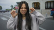 © Krakenimages.com - Young chinese woman outdoors on a street making playful gestures with her hands, creating a dynamic and lively atmosphere in an urban setting.