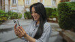 © Krakenimages.com - Chinese woman smiling on a street, holding smartphone outdoors, capturing a lively urban atmosphere.