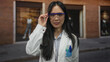 © Krakenimages.com - Young chinese woman scientist in white uniform standing confidently outdoors with arms crossed, wearing safety glasses on a street, showcasing professional determination and expertise.