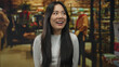 © Krakenimages.com - Chinese woman smiling indoors wearing a white shirt in a vibrant clothing store, capturing a joyful moment amidst a modern retail environment with stylish displays.