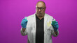 © Krakenimages.com - Man doctor, senior hispanic in lab coat wearing blue gloves holds dental floss container and toothpaste tube while examining them in studio; skepticism hygiene.