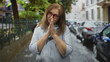 © Krakenimages.com - Senior hispanic woman wearing red glasses with clasped hands in a pleading gesture on a city street near parked cars and iron fence; hope plea.