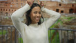 © Krakenimages.com - Hispanic woman smiling with playful gestures near roman ruins outdoors.