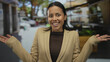 © Krakenimages.com - Woman smiling in a beige blazer at outdoor restaurant terrace with street and cars in background under sunny sky suggesting a lively city vibe.