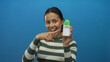 © Krakenimages.com - Hispanic woman showcasing deodorant against an isolated blue wall, highlighting personal care products with a vibrant background.