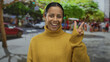 © Krakenimages.com - Woman smiling and gesturing peace sign on bustling street with trees showing vibrant urban scene.