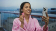 © Krakenimages.com - Woman holding cup smiling on cruise deck in bathrobe while talking on phone with seaside view.