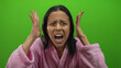 © Krakenimages.com - Woman wearing pink bathrobe stands against vibrant green background, expressing frustration with hands on head, creating a striking contrast between her attire and surroundings.