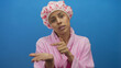 © Krakenimages.com - Young hispanic woman in a pink bathrobe makes a gesture asking for money against a blue background with a shower cap and expressive look