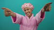 © Krakenimages.com - Woman in pink bathrobe and shower cap smiling against isolated green background wall, conveying warmth and comfort in a simple yet vibrant setting.