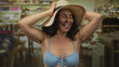 © Krakenimages.com - Woman smiling in bikini and sunhat indoors at clothing store filled with vibrant items and colorful decor showcasing cheerful atmosphere.