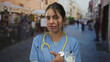© Krakenimages.com - Young woman doctor in blue uniform with yellow stethoscope and nametag points finger on a street; disgust.