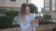 © Krakenimages.com - Woman smiling while using smartphone on city street showcasing happiness, technology, urban lifestyle, and outdoor engagement in an everyday setting.