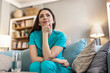 © Jelena Stanojkovic - Calm, thinking and a nurse or woman on the sofa to relax from a career in healthcare in a house. Smile, peace and a medical employee or doctor with an idea or vision on the couch for a memory.
