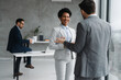 © Novak - African American business woman and man discussing a project in a modern office with a colleague working in the background.