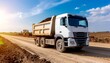 © grecosta - White dump truck transporting dark soil on rural road, agriculture, farming, and earthwork concept.
