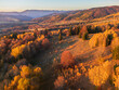 © AmazingAerialAgency - Aerial view of a vibrant tapestry of autumn foliage blanketing rolling hills under a serene sky, Polana, Krasna roven, Slovakia.