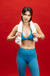 © wedmoments.stock - Fit woman posing with towel on shoulders on red isolated background. Exercise, wellness and fitness concept.