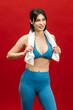 © wedmoments.stock - Sporty woman posing with towel on shoulders on red isolated background. Fitness, wellness and active lifestyle concept.