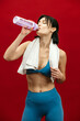 © wedmoments.stock - Beautiful sporty woman drinking water against a bold red background. Concept of hydration, fitness motivation, healthy lifestyle, energy balance and active modern living. Studio shot with strong visua
