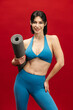 © wedmoments.stock - Fit woman with a sports mat on red isolated background. Exercise, wellness and fitness concept.