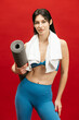 © wedmoments.stock - Athletic female model holding fitness mat on red isolated background. Active lifestyle, workout and fitness concept.