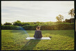© Ryan Tuttle/Stocksy - Woman doing yoga at sunrise on a lawn