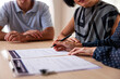 © Jovo Jovanovic/Stocksy - Couple signing documents with advisor at table.
