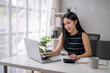 © Wasana - Focused businesswoman working on laptop and calculator