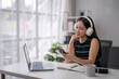 © Wasana - Young woman engaging in remote work with headphones