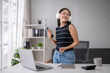 © Wasana - Young woman enjoying music while working remotely