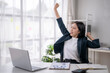 © Wasana - Young professional stretching at her desk in office