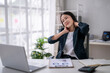 © Wasana - Businesswoman suffering from neck pain while working on laptop in office