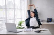 © Wasana - Asian office worker taking a break and stretching arms at workplace