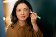 © Artcore Studio/Stocksy - Woman applying makeup at mirror