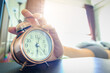 © Media  - Hand reaching out to turn off or snooze a vintage alarm clock in the bedroom at morning, waking up for a new day and daily routine .health and relaxation concepts.