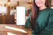© Farknot Architect - Mockup image of a woman holding and showing a mobile phone with blank white screen in cafe