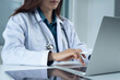 © tippapatt - Close up, doctor working on laptop computer with digital tablet on office table. Female doctor searching the patient health information, using laptop and tablet. healthcare and medicine concept