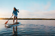 © BuyoutReese08/peopleimages.com - Holiday, back of woman and paddle boarding on lake for vacation activity, adventure and hobby. Space, person or balance on paddleboard on water for summer getaway, sunrise SUP or exploring on weekend