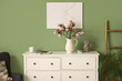 © Pixel-Shot - Chest of drawers with blooming magnolia branches near green wall in room