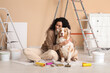 © Pixel-Shot - Happy female African-American painter with equipment and cute Australian Shepherd dog sitting during repair in new house