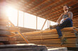 © Pixel-Shot - Male carpenter sitting on wooden planks at sawmill