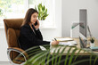 © Pixel-Shot - Female office worker talking with mobile phone and sitting on armchair at workplace in light office