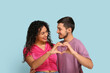 © Pixel-Shot - Young couple making heart with hands on blue background. Valentine's day celebration
