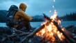 © Pinklife - A lone hiker sits by a crackling campfire, gazing at a serene lakeside under rainy skies. This image highlights solitude, reflection, and the beauty of nature.