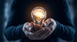 © Miktuja - A person holding a glowing lightbulb with an illuminated brain inside, close-up view of hands and the bulb