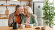 © Fadilah - affectionate senior couple smiling and holding hands over coffee in their modern home kitchen symbolizing lasting love companionship and healthy aging.