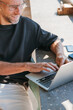 © Soloviova Liudmyla - Professional male digital nomad and successful day trader working on laptop at outdoor cafe terrace during summer vacation while enjoying freedom of remote work lifestyle and modern digital technology