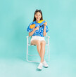 © sitthiphong - Songkran festival in Thailand, Happy smiling young Asian woman in summer sit in deckchair and holding water guns in blue background.